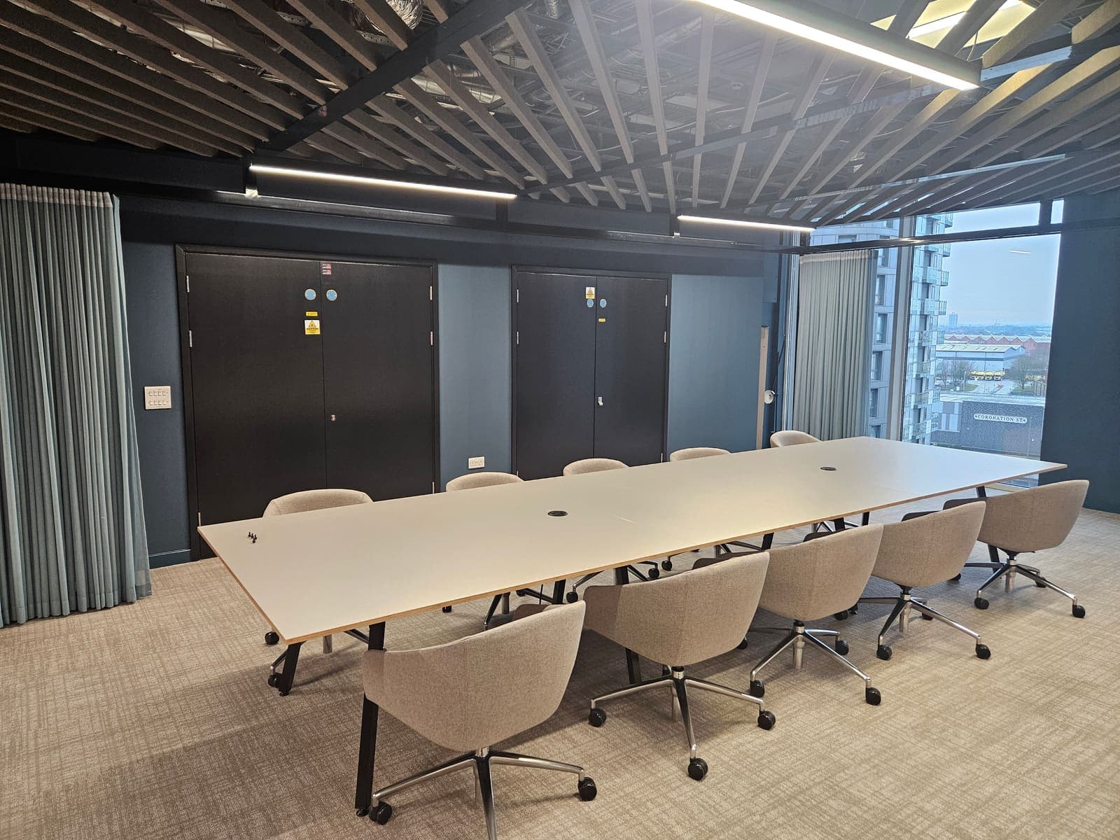 Boardroom with a black acoustic baffle raft ceiling installed by Stockport Suspended Ceilings at MediaCityUK