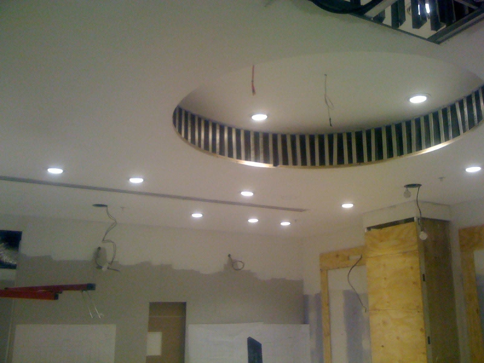 Finished circular MF drum ceiling with slatted metallic perimeter and downlights at Thomas Sabo, Milton Keynes